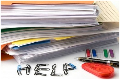 A stack of papers and office supplies, with the word "help" spelled out using paper clips